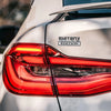 Close-up view of a red taillight on a silver car with a SHITBOX EDITION logo decal.