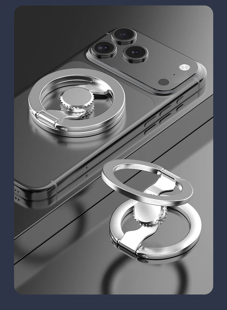 A silver magnetic phone ring stand with a dual-sided grip is shown resting on a dark surface.