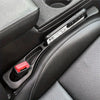 A close-up view of a car seat gap filler organizer with a red switch and a silver electronic component in a black car interio