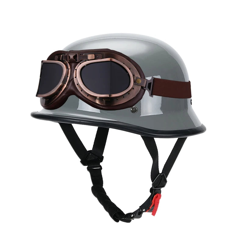 A silver half-helmet with brown goggles and a black strap harness for motorcycle or EV safety.