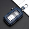 A dark blue leather key protector pouch with a clear window and silver clasp resting on a black surface.