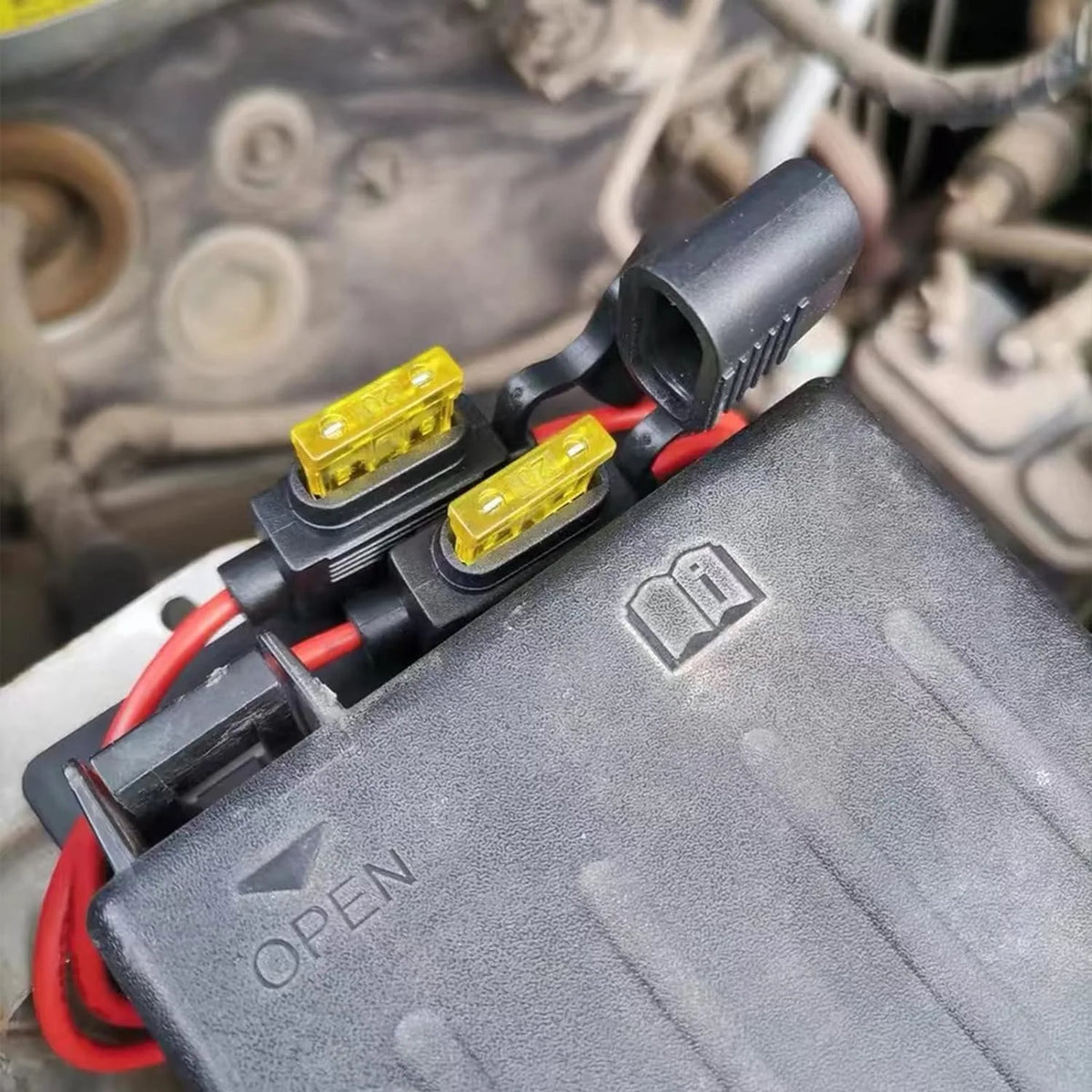A black assortment kit of blade fuses with yellow connectors and red wires is shown on a gray plastic housing.
