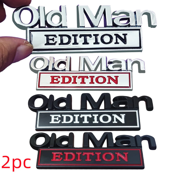 A set of three metal emblems featuring the text Old Man EDITION in various colors and finishes.