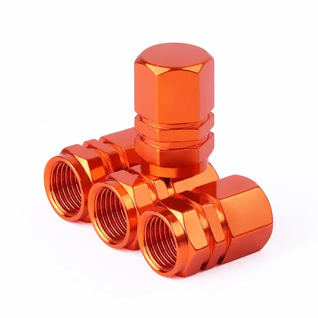 A set of four bright orange hex aluminum alloy tire valve caps stacked and displayed on a white background.