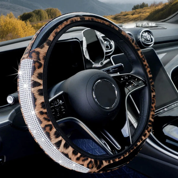 A close-up of a black steering wheel covered in leopard print material with sparkling rhinestone accents.