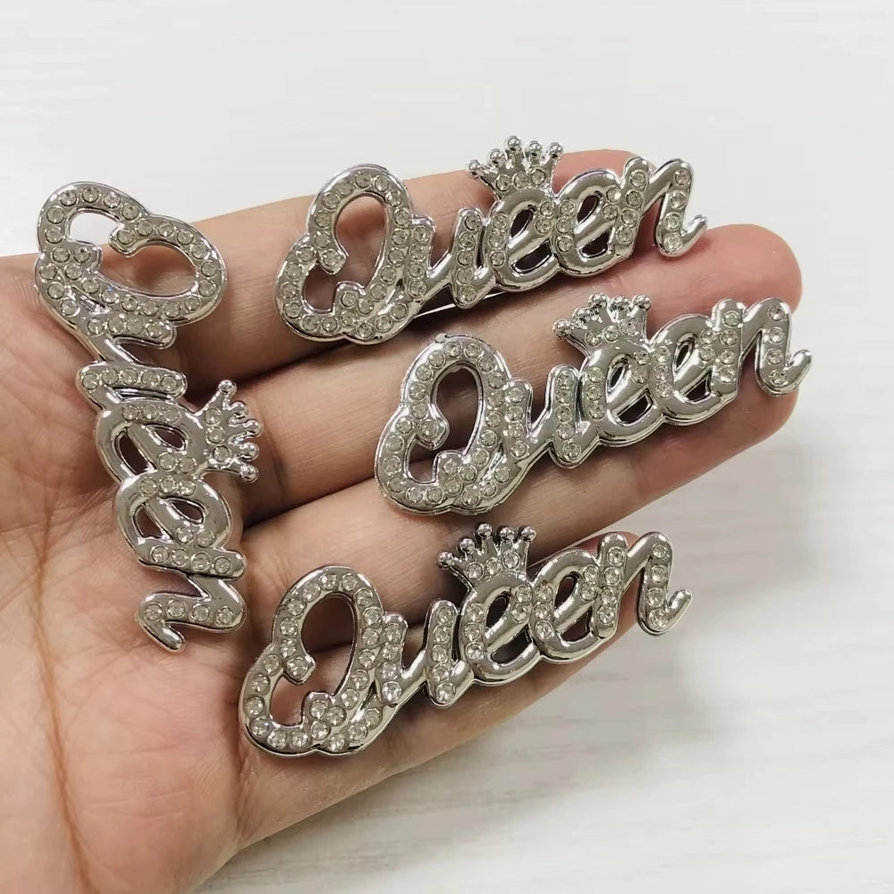 حروف مرصعة بالكريستال الفضي تكوّن كلمة QUEEN على يد