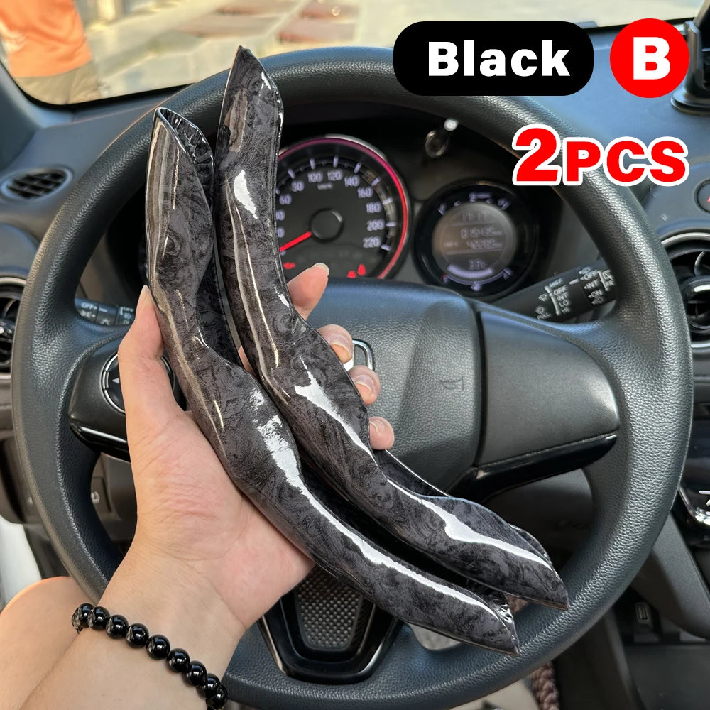 Black steering wheel booster covers, two pieces, shown in a hand on a car steering wheel.