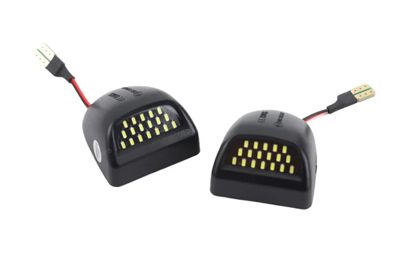 Un par de luces de matrícula LED de alta intensidad, una negra y otra gris oscura, mostradas contra un fondo blanco.
