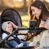 A woman is holding a baby in a bike phone holder with a hidden tracker for motorcycle safety during sunset.