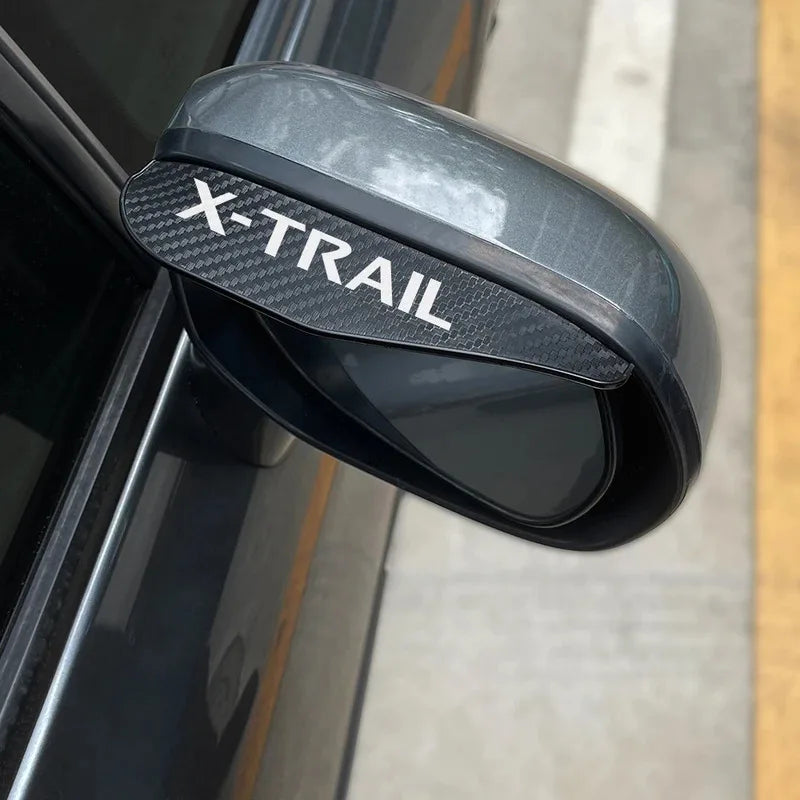 Black X-Trail car rain guard eyebrow cover placed over a vehicle's rearview mirror.