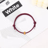 A maroon heart-shaped fitness tracker bracelet is displayed on a white background next to text that reads and White.
