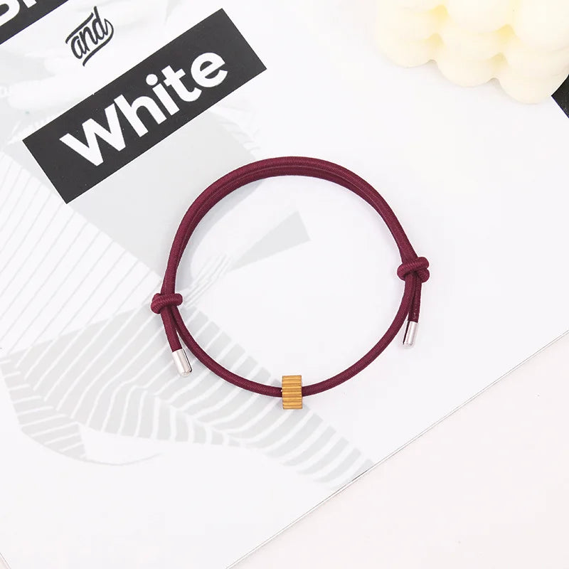 A maroon heart-shaped fitness tracker bracelet is displayed on a white background next to text that reads and White.