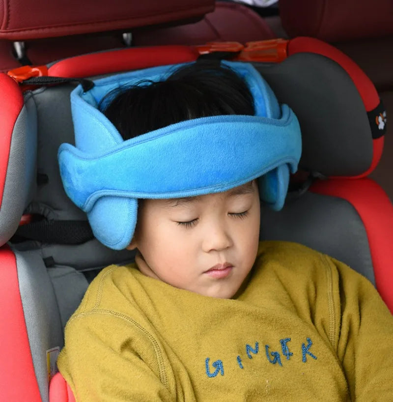 Ein Baby ruht in einem Autositze mit einem blauen Kopfstützenkissen und trägt ein gelbes Hemd.
