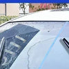 Close-up view of a car window with rain repellent spray applied, showing water beading on the glass.