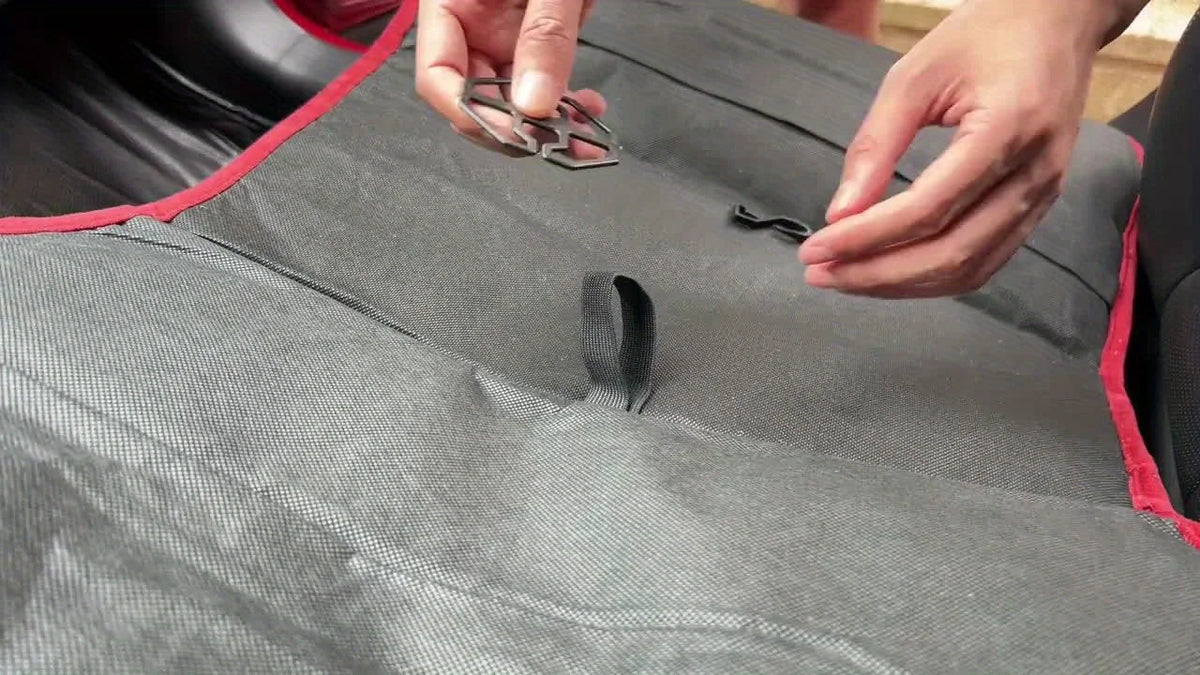 Hände passen ein schwarzes Luxus-Plüsch-Autositzkissen an, zeigt die Stofftextur und die Nähte.