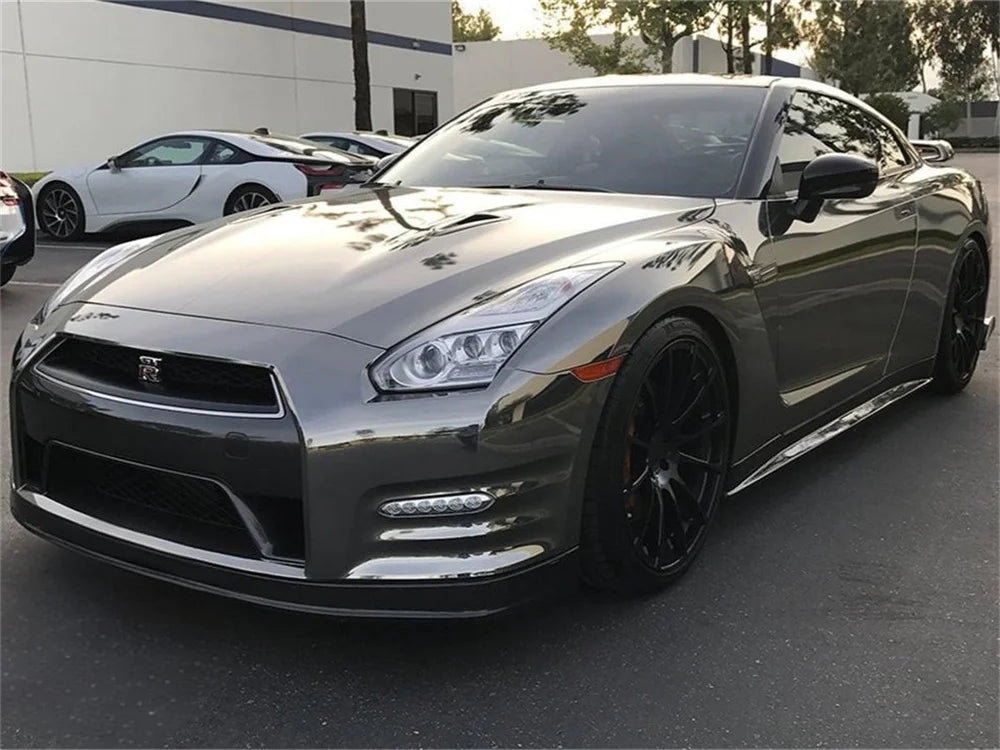 A silver Nissan GT-R sports car parked outdoors with other vehicles in the background.