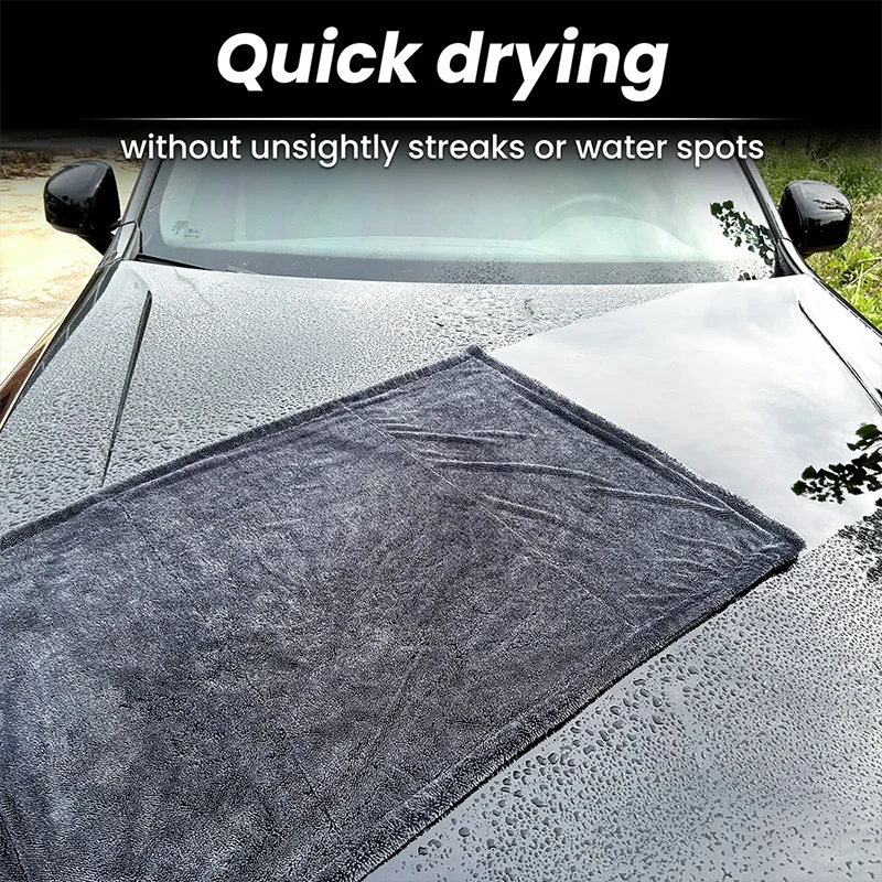 A black microfiber cleaning cloth is placed on the hood of a car, demonstrating quick drying without streaks.