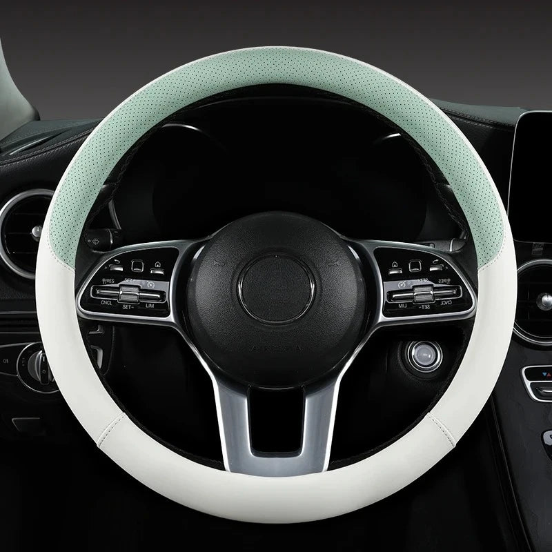 A close-up view of a steering wheel with a light green perforated leather cover and black accents.