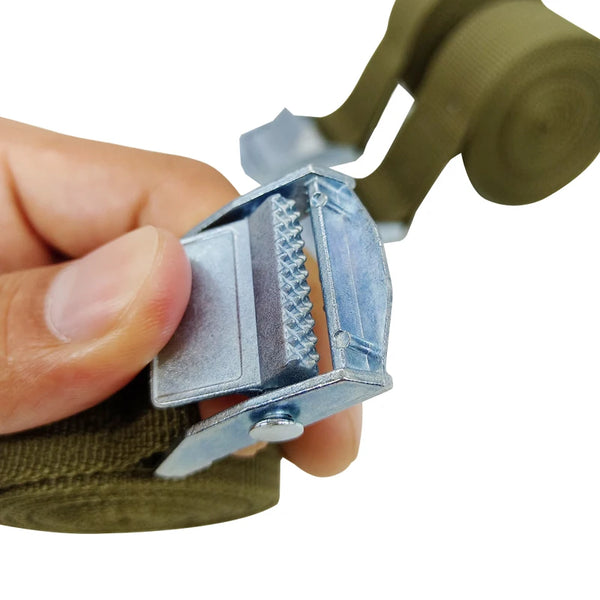A hand is holding a heavy duty cargo strap with a buckle tie-down belt and a green strap.