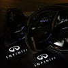 Interior view of a car door with illuminated light lines, showcasing the Infiniti brand logo on the floor.