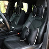 Black ergonomic car headrest pillow with a bow design shown inside a vehicle cabin.