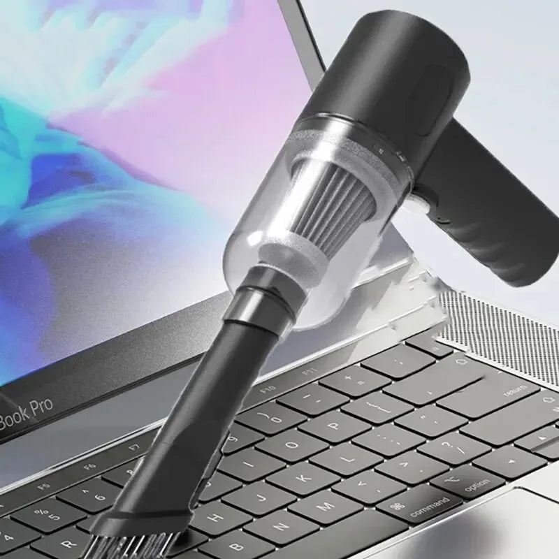 Gros plan d'un aspirateur de voiture sans fil haute puissance posé sur un clavier d'ordinateur portable.
