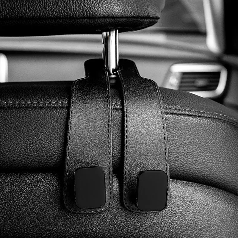 Close-up of black car headrest hooks used for organizing bags or items.