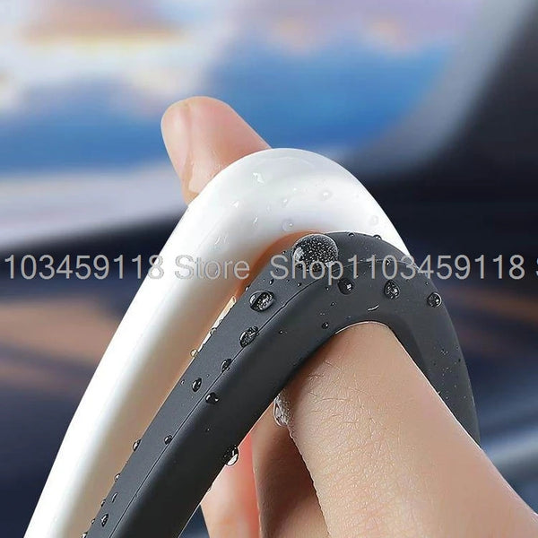 A hand is holding a silicone screen frame protector for a car, showing the white and black protective frame.