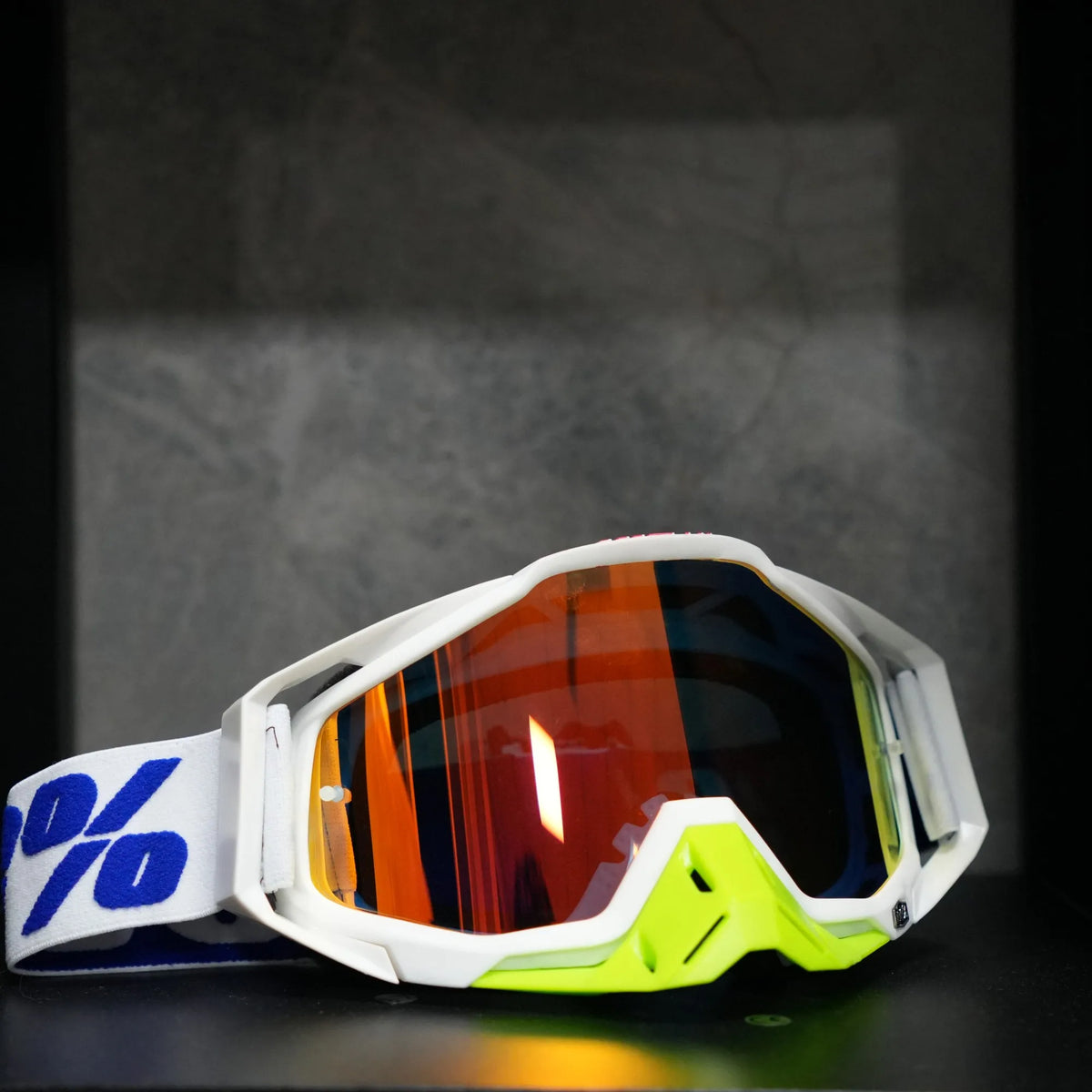 A pair of white and neon yellow motocross goggles resting on a dark surface.