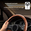 A hand grips an anti-slip steering wheel cover with peach wood grain on a car interior.