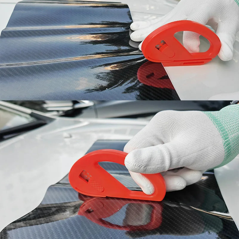 A hand wearing a white glove is using an orange vinyl wrap installation tool on a glossy black car surface.