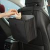 A hand places a tissue into the storage compartment of a black car trash organizer.