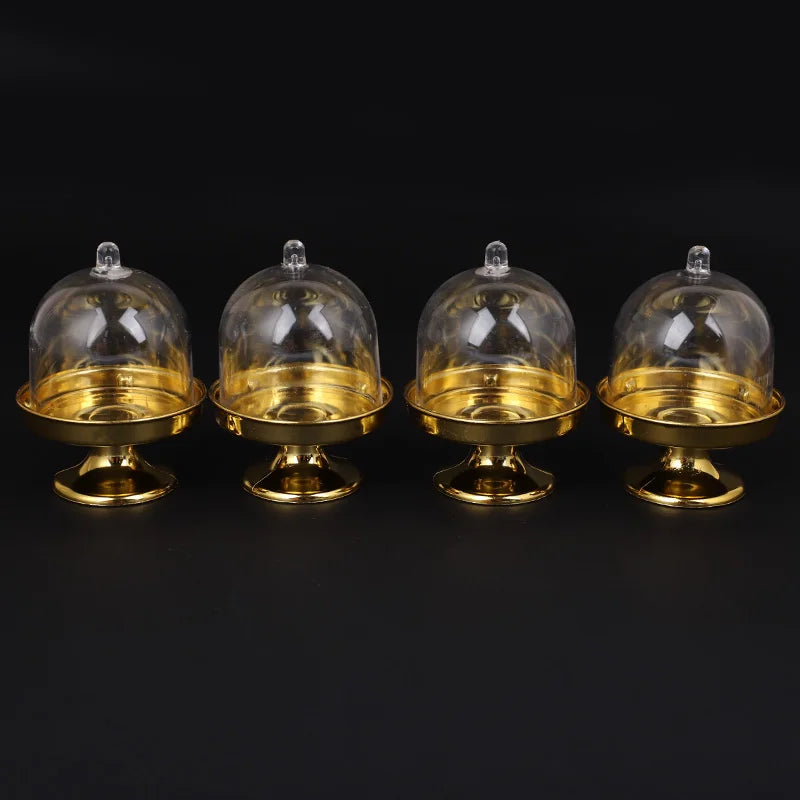 Set von vier Mini-Goldglas-Cupcake-Display-Ständern mit klaren Kuppeln.