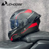 Casque de moto modulaire noir et rouge DOT posé sur une surface en cuir noir.