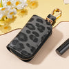 A black leopard print car key holder with a gold-colored clasp resting on a light background.