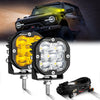 A pair of powerful LED off-road driving lights mounted on a bar, with a modified black Jeep in the background.