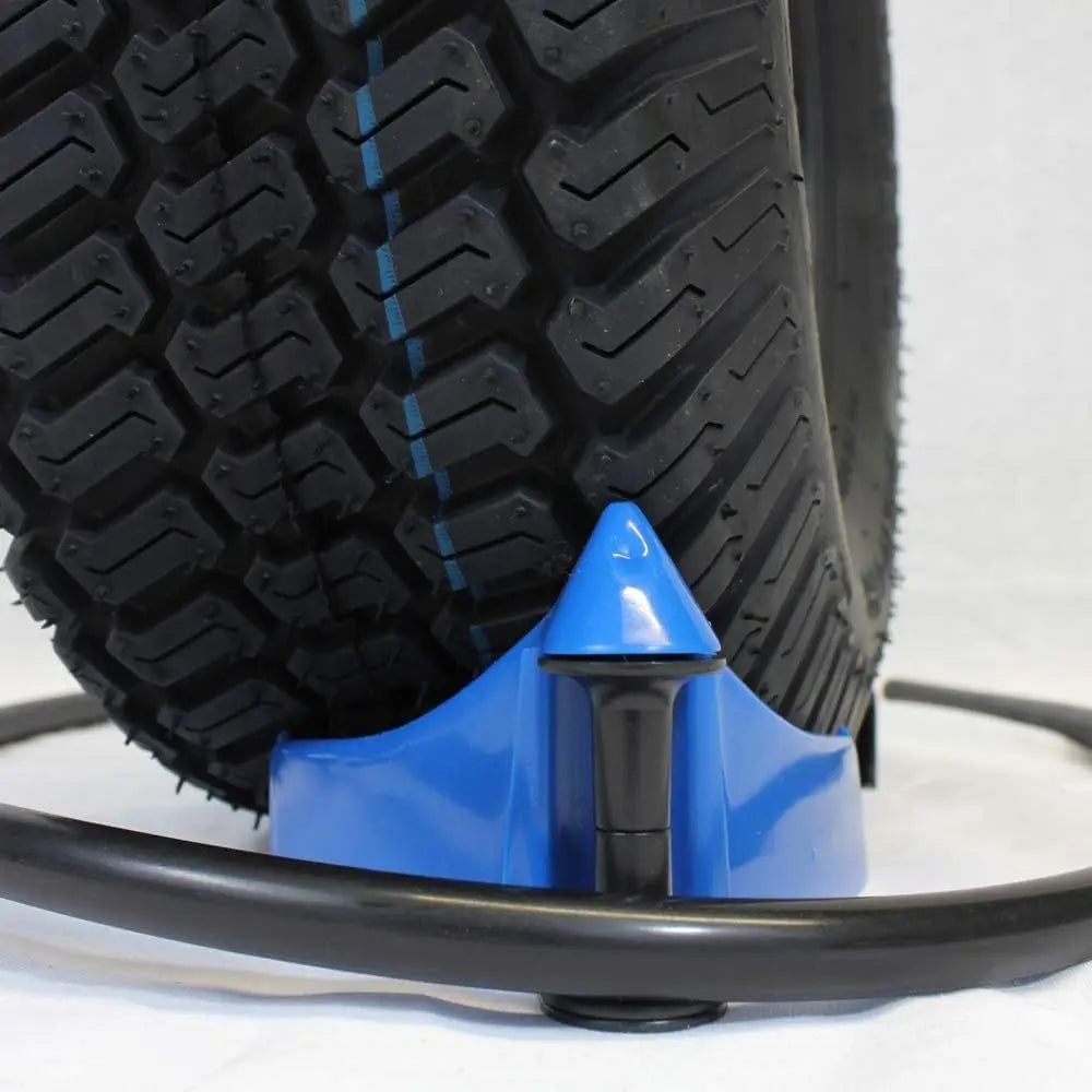 A close-up view of a blue tire wedge tool with a black hose and a treaded tire.
