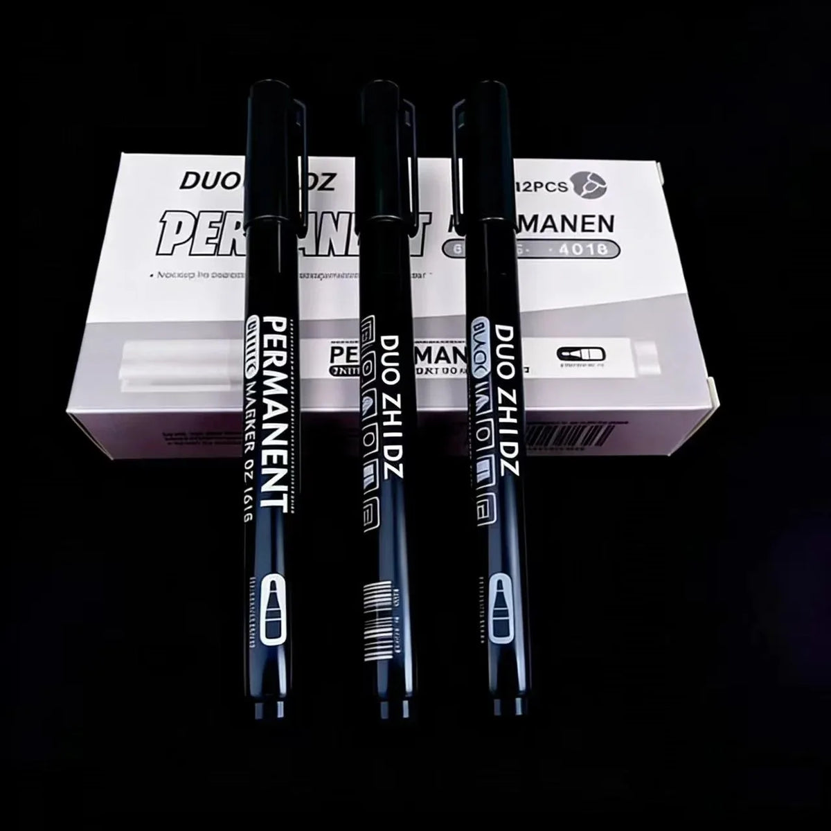 Three black and white permanent paint markers are displayed in a box for art and craft use.
