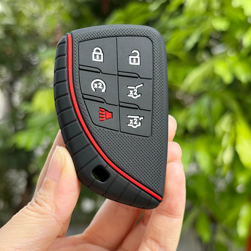 A hand holds a black universal key fob cover with multiple buttons for Chevy and GMC trucks.