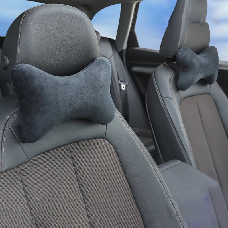 A close-up view of a dark gray memory foam car neck pillow on a vehicle seat.