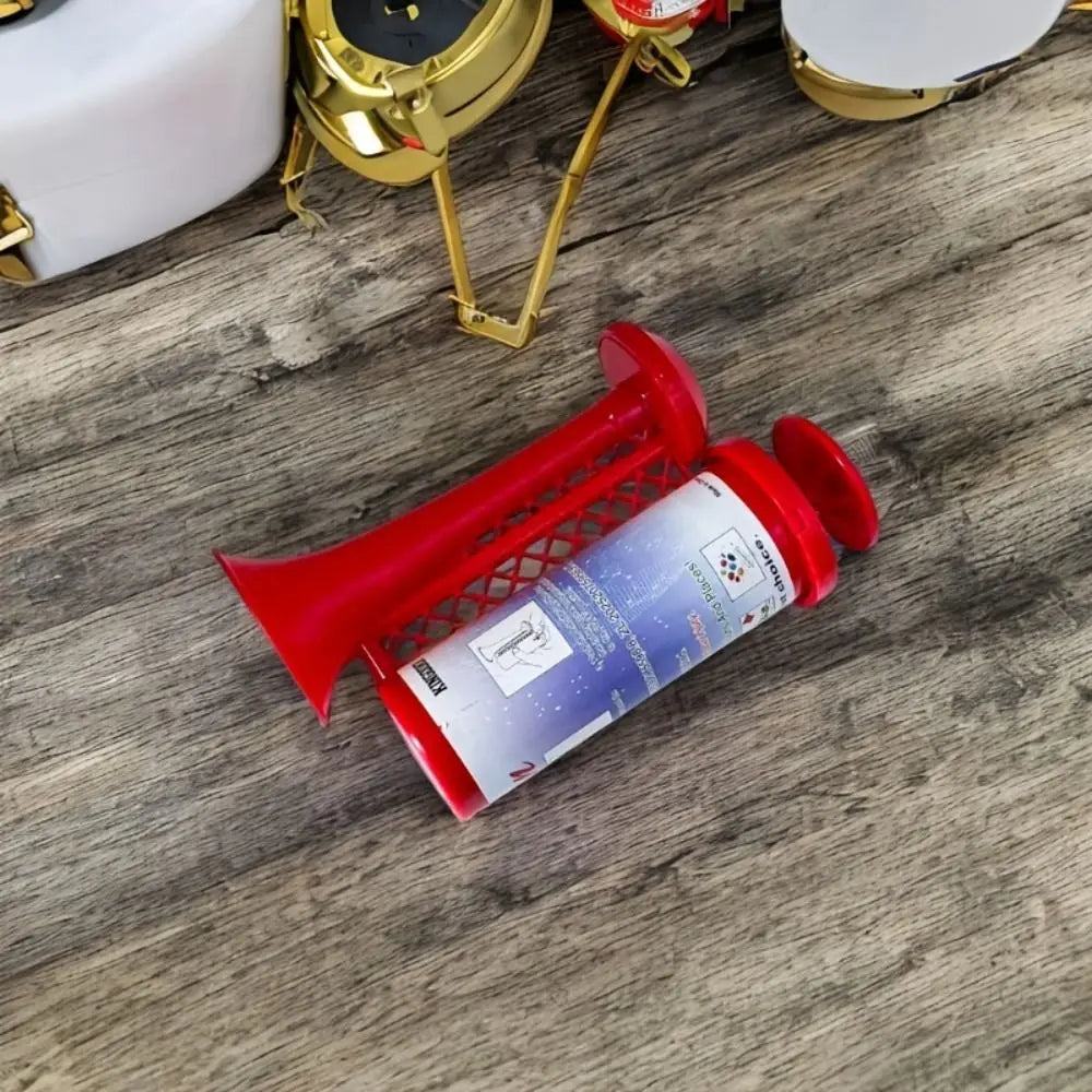 A red portable air horn is shown lying on a wooden surface next to gold-colored vehicle alarm components.