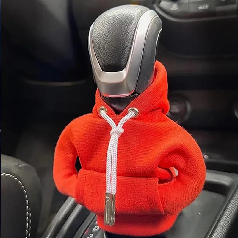 An orange knit hoodie is placed on a car gear shift knob.