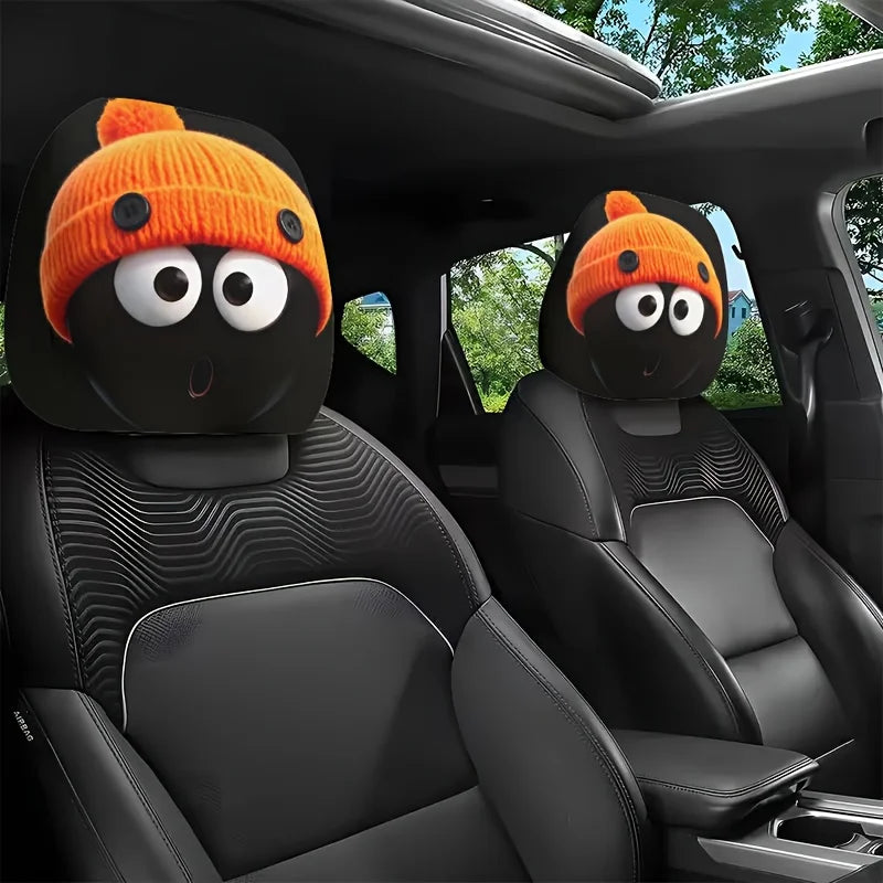 Un paire de housses pour tête de siège orange tricotées avec des yeux noirs sont montrées à l'intérieur d'une voiture.