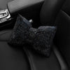 Almohada de cuello para coche de cristal de imitación con pedrería negra sobre un asiento oscuro de coche.