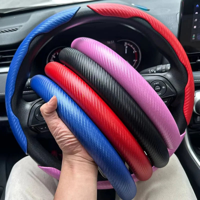 Eine Hand hält eine Carbonfaser-Lenkrad-Boosterabdeckung mit mehrfarbigen Griffen in einer Auto-Innenausstattung.