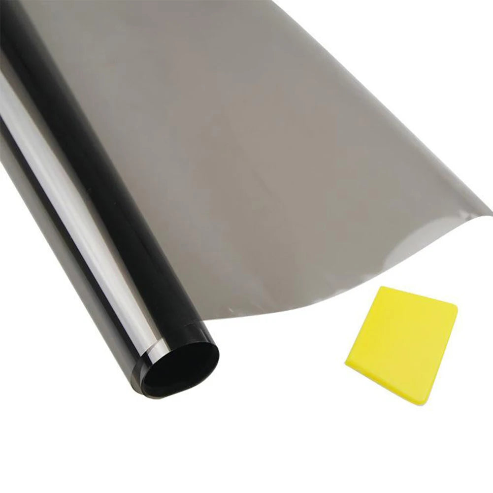 A roll of dark tint film is shown partially applied to a clear window surface, with a yellow square piece nearby.