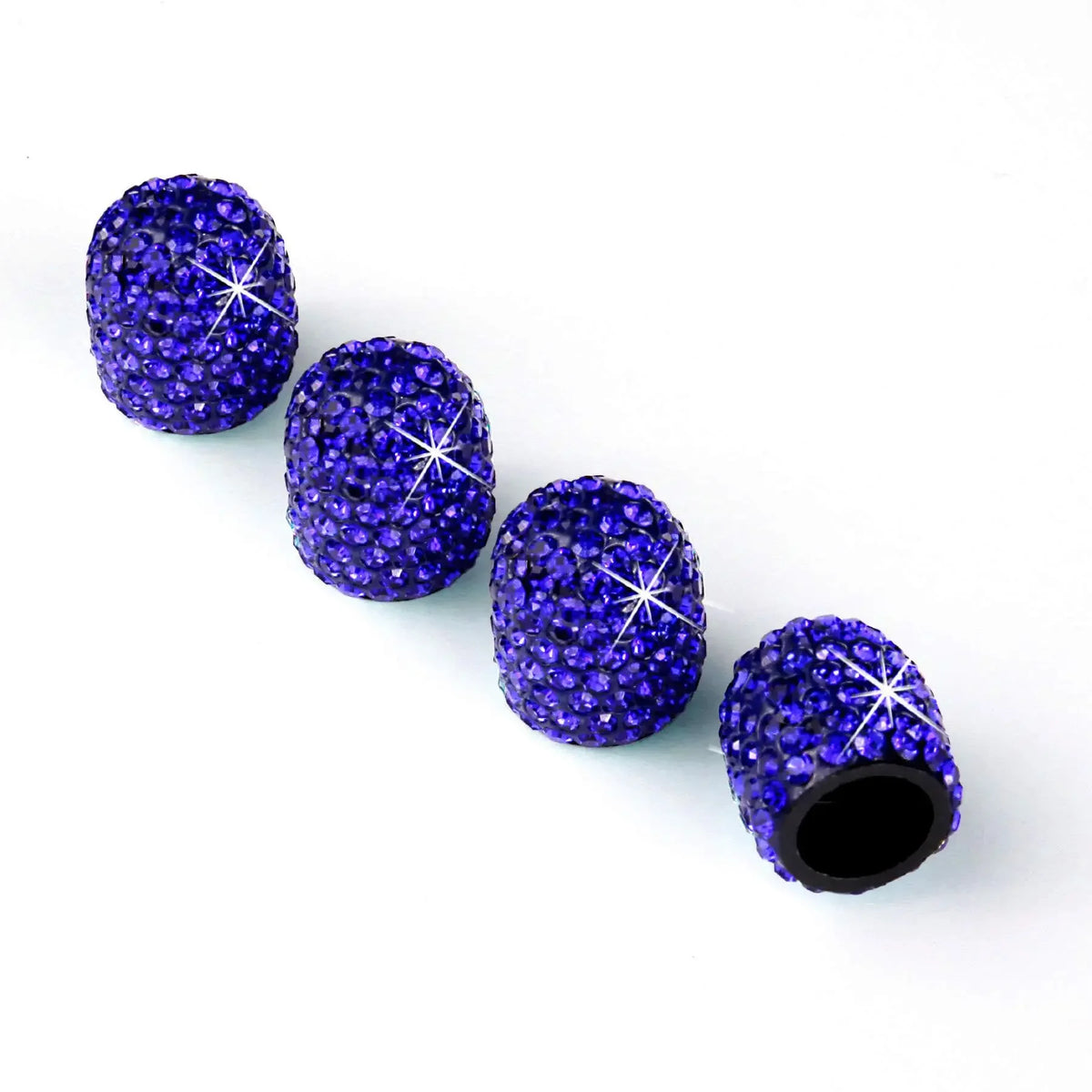Eine Reihe von neun tiefvioletten Glitzer-Diamant-Radkappen für Auto-Ventile auf weißem Hintergrund.