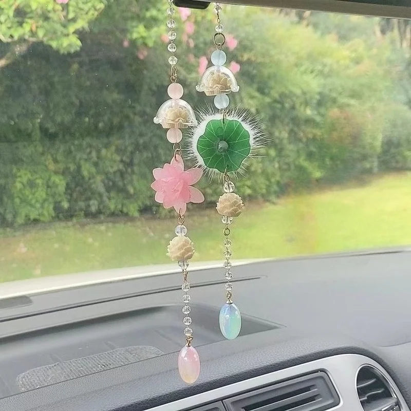 A pink lotus car pendant ornament featuring multiple dangling beads and a green feather detail.