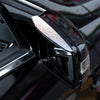 A close-up of a black car's rearview mirror with a rhinestone visor installed on the top.