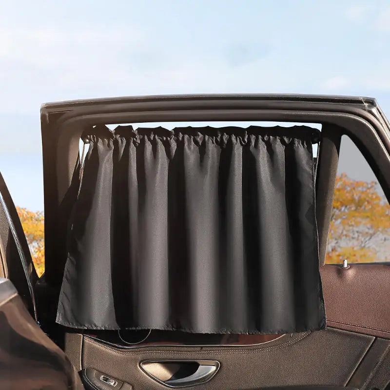 A black suction cup window sunshade is installed in a car window frame.